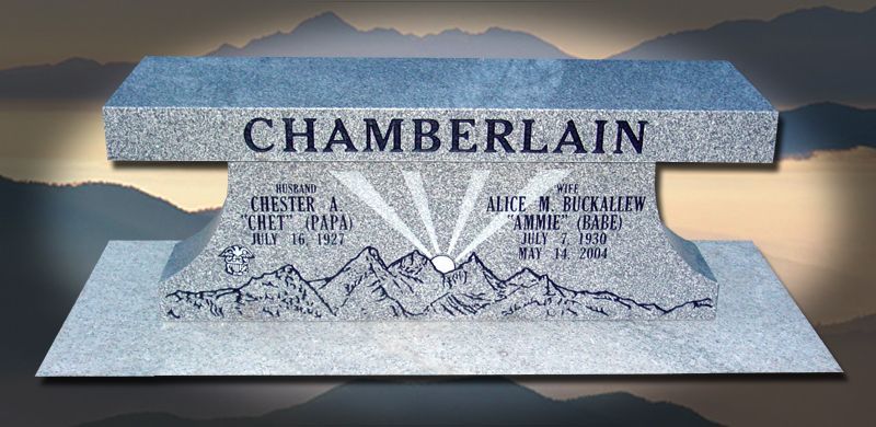 A granite memorial bench with the Chamberlain family name, mountain scene, and dates.