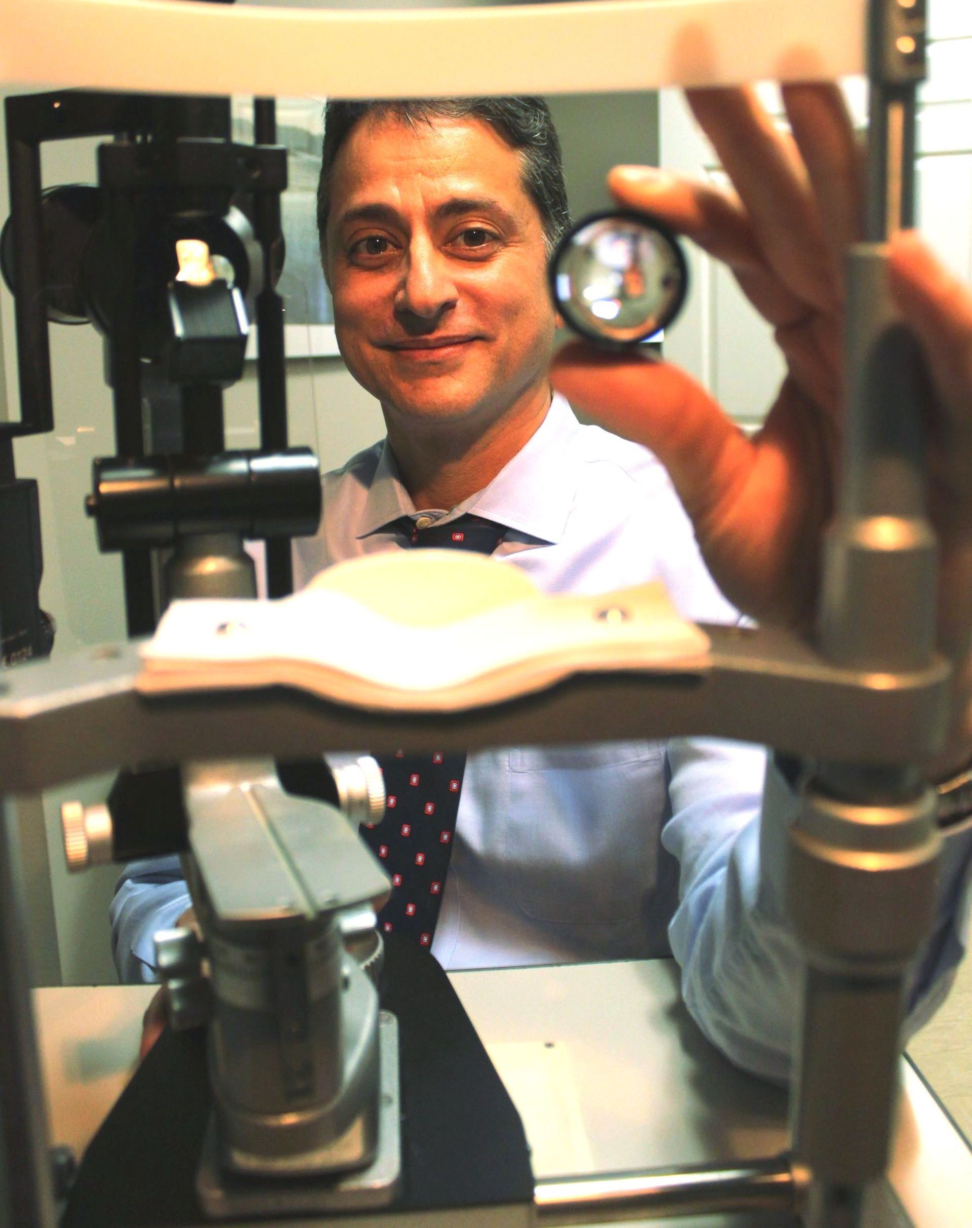 Dr. Quereshi holding up magnifying lens for eye exam