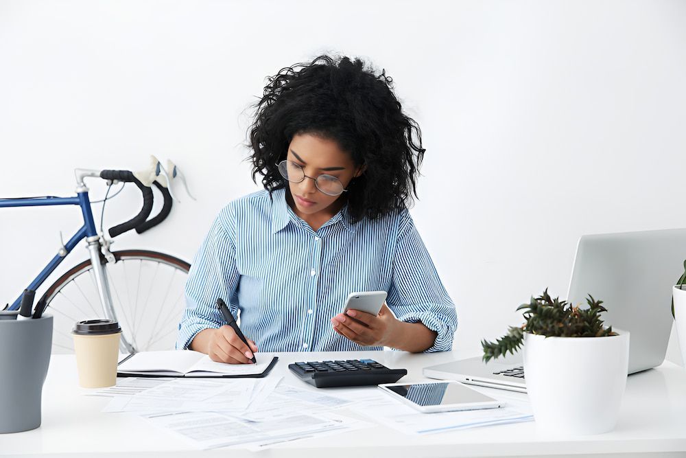 A Woman Is Sitting At A Desk Using A Cell Phone — Border Bandag Tyre Service In South Albury, NSW