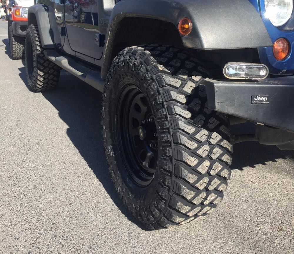 Large Tyre Mounted on The Rear of A Blue Jeep