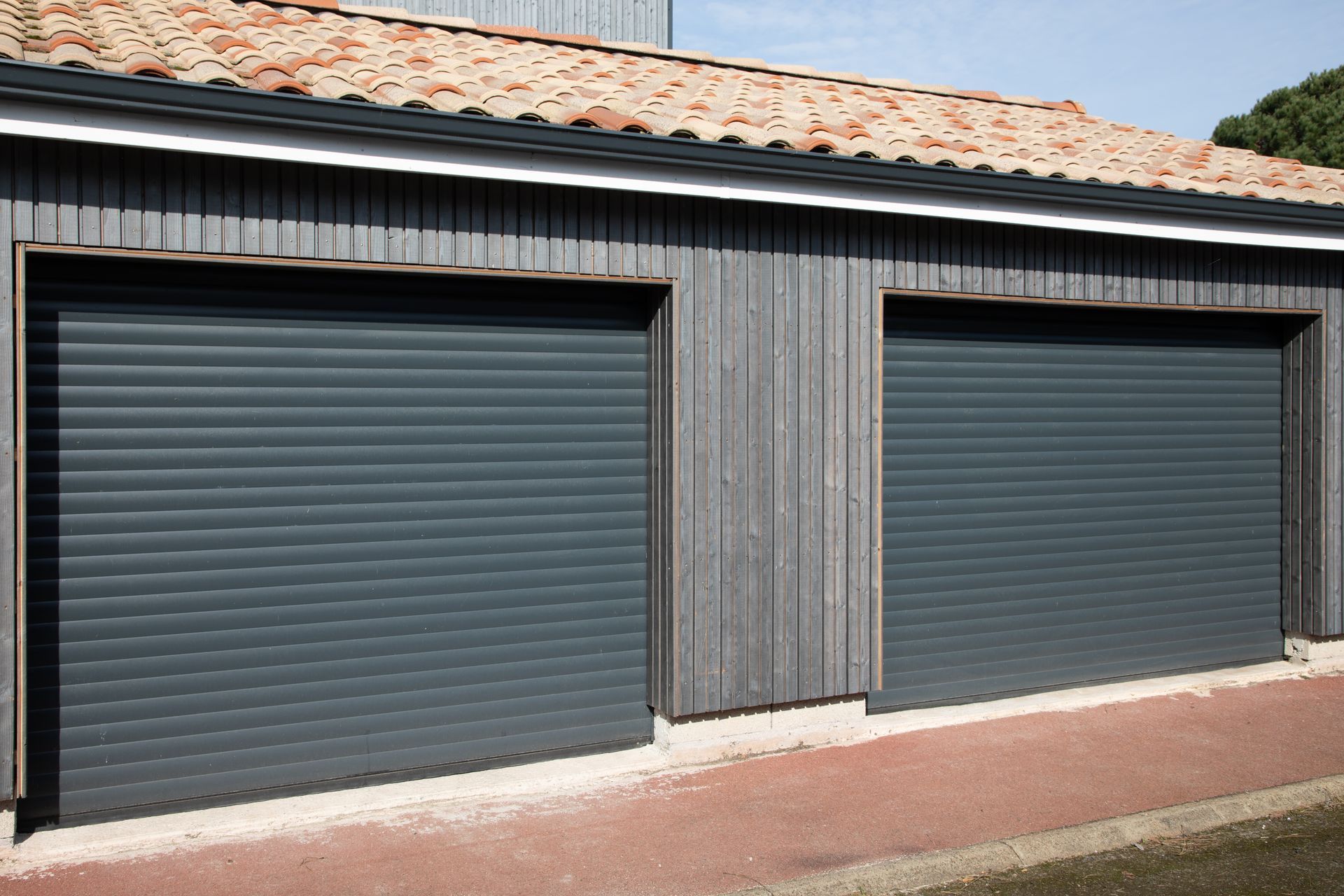 Two garage doors with roller shutters on the side of a building