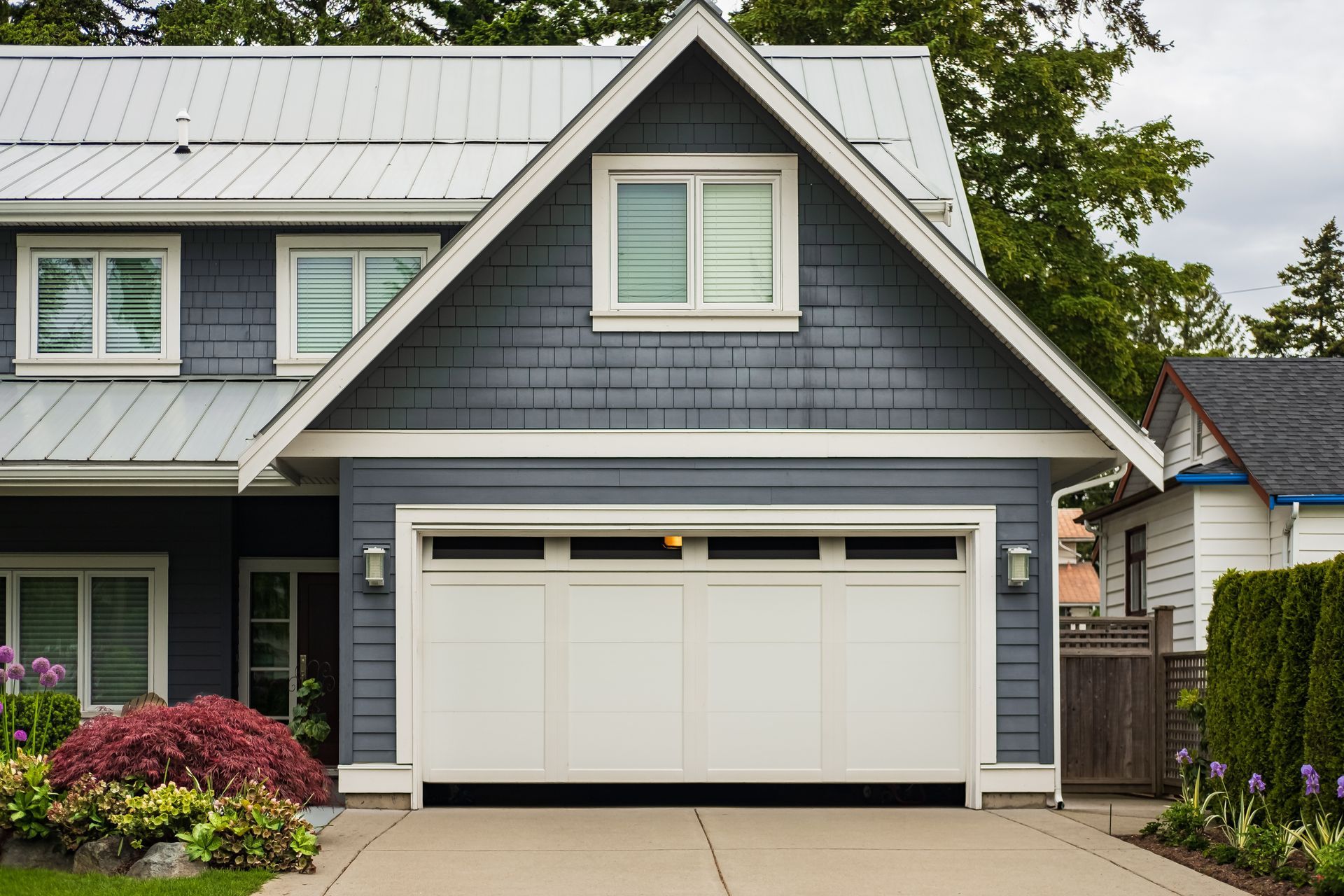 A blue house with a white garage door and a white roof.