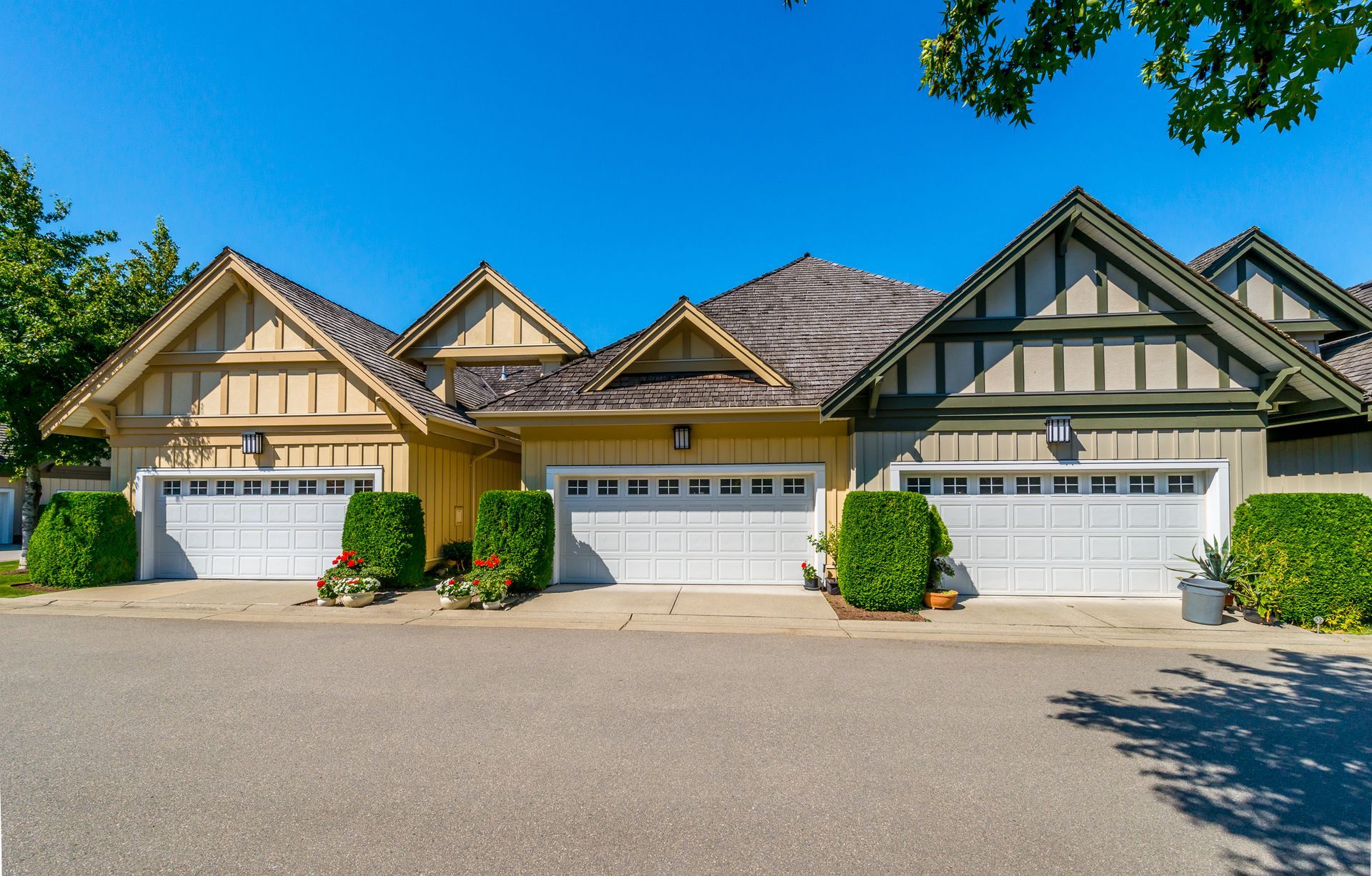A row of houses with white garage doors on a sunny day