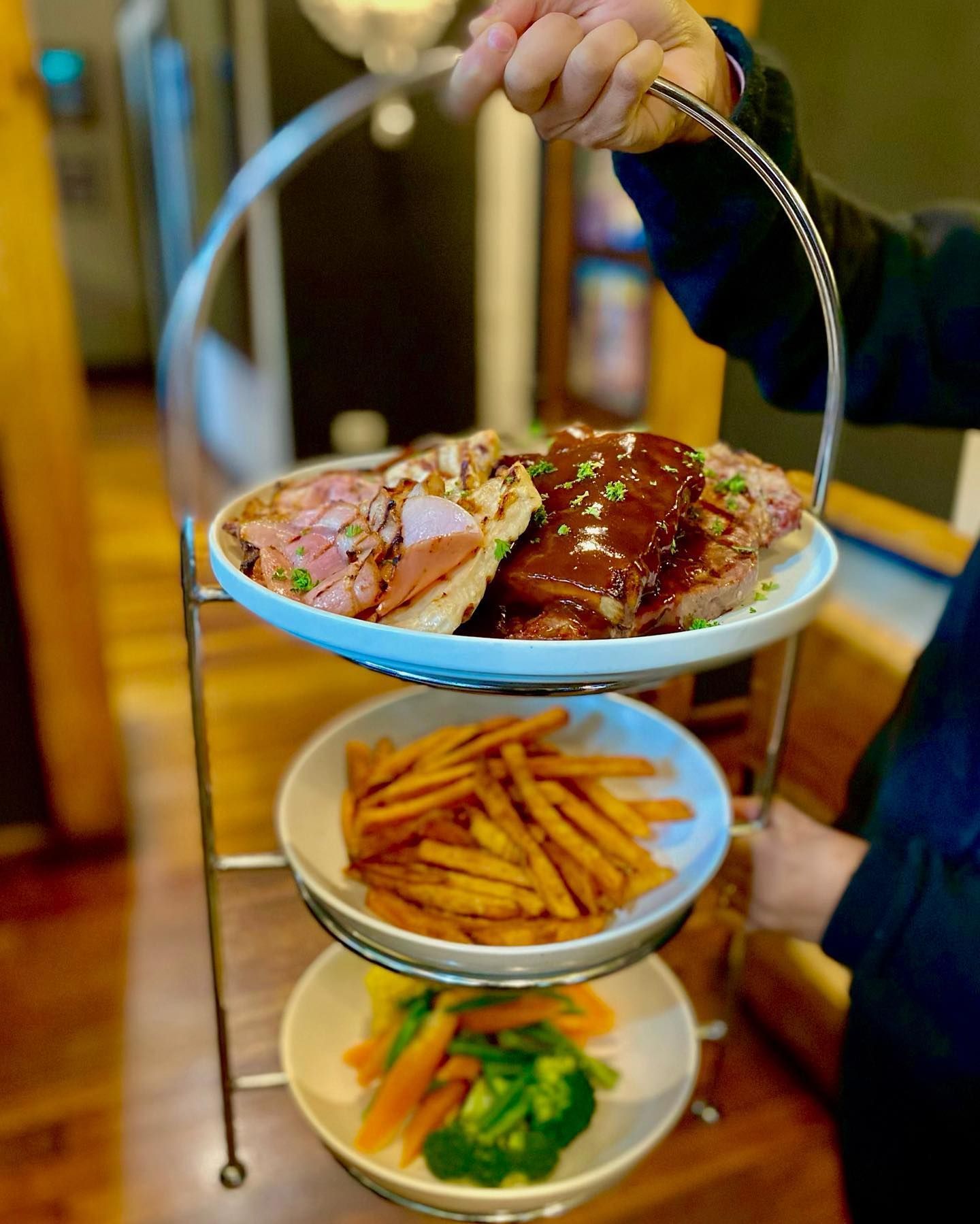 A Person is Holding a Three Tiered Tray of Food — The Shire Bar & Grill In Dubbo, NSW