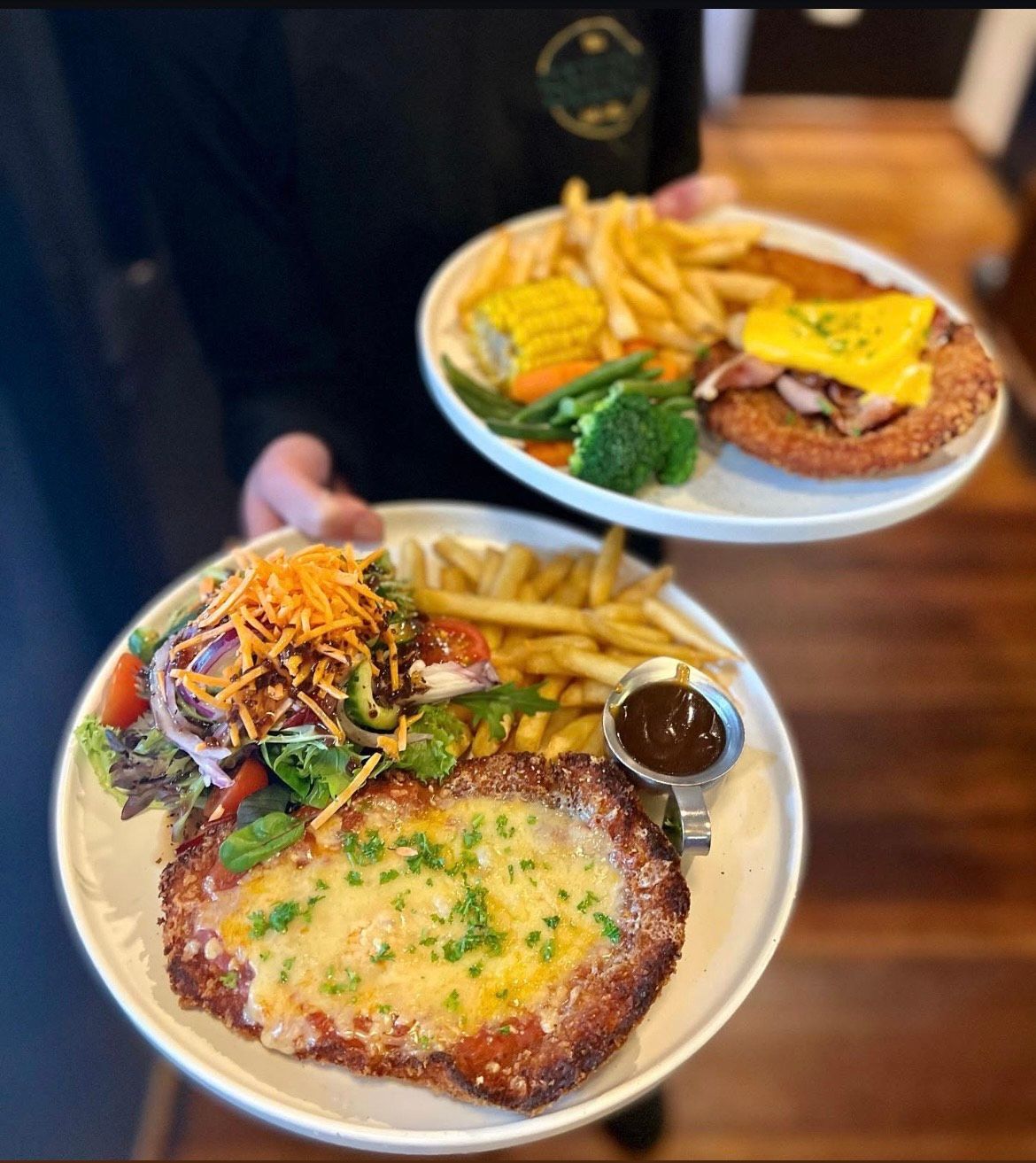 Chicken parmigiana dishes with chips, salad, and vegetables.— The Shire Bar & Grill In Dubbo, NSW