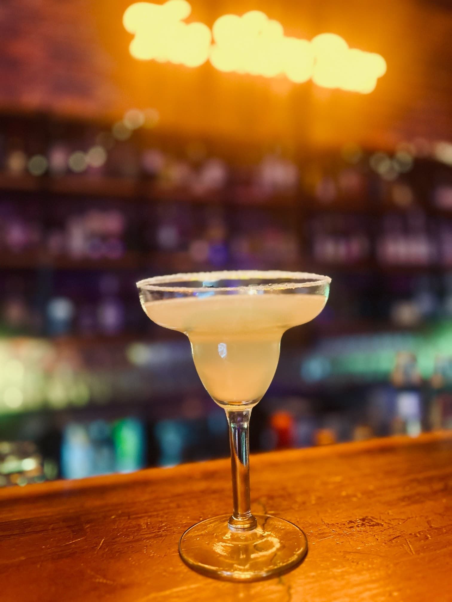 Margarita Cocktail in a Salt-rimmed Glass on a Wooden Bar, With a Blurred Bar Background — The Shire Bar & Grill In Dubbo, NSW