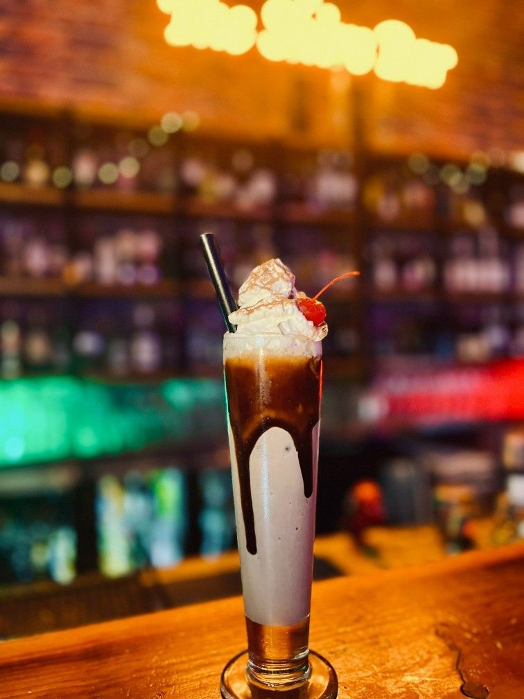 Tall Cocktail With Whipped Cream, Cherry, and Chocolate Syrup in a Bar Setting — The Shire Bar & Grill In Dubbo, NSW