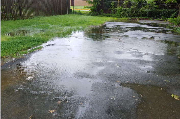 Water pooling on a Long Island asphalt driveway, resulting in needed asphalt repair.