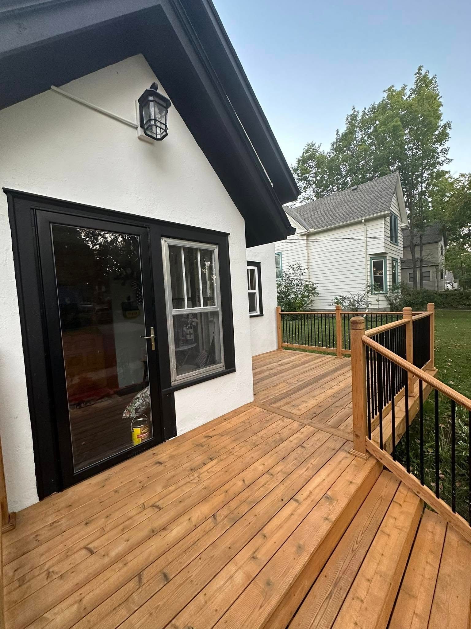 A small white house with a wooden deck in front of it.