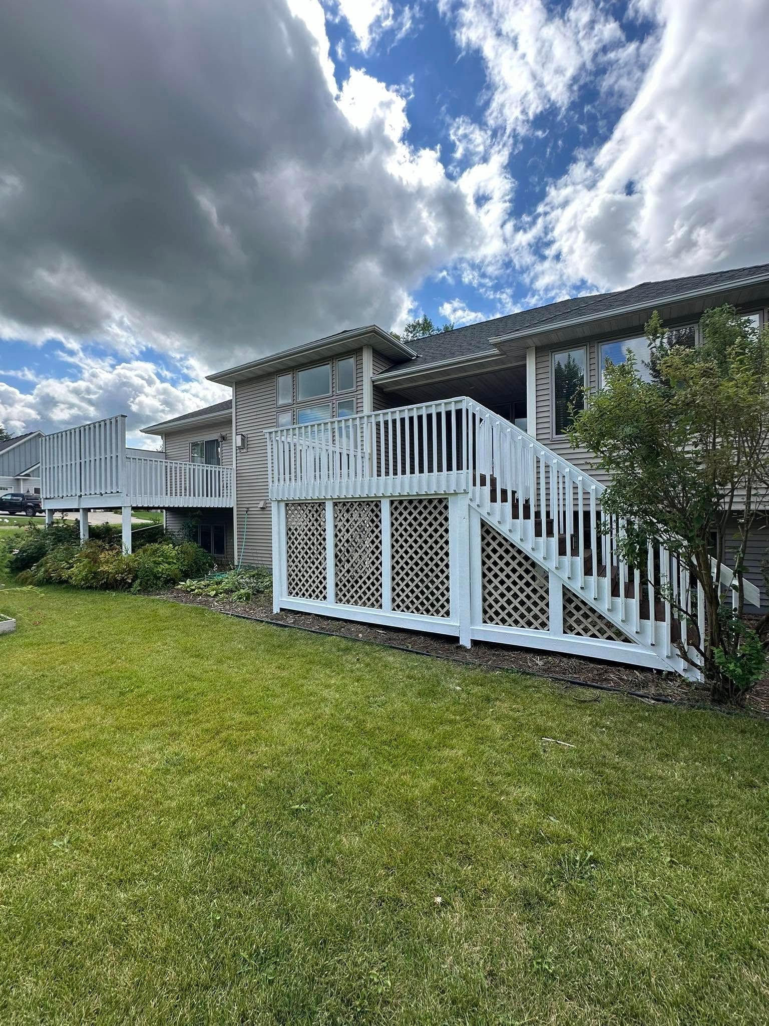 A house with a large deck and stairs in the backyard.