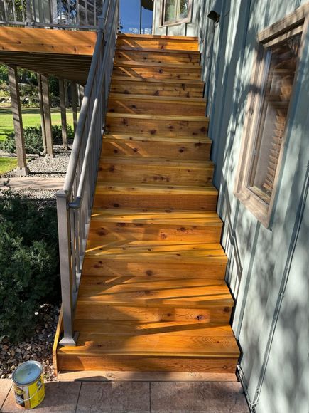 A wooden deck with stairs leading up to a house.