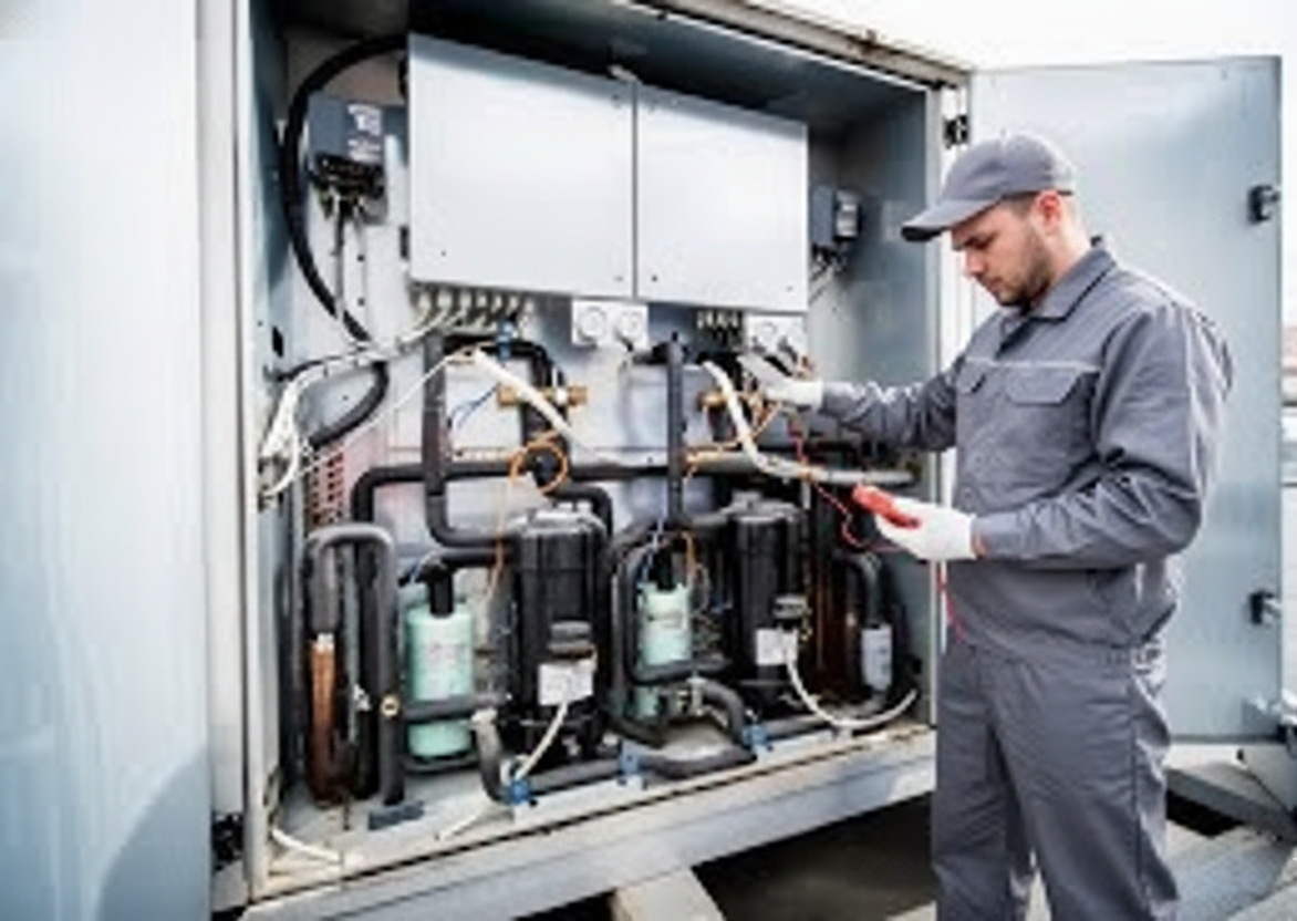 Technician in gray coveralls, examining HVAC unit with multimeter, outdoors.