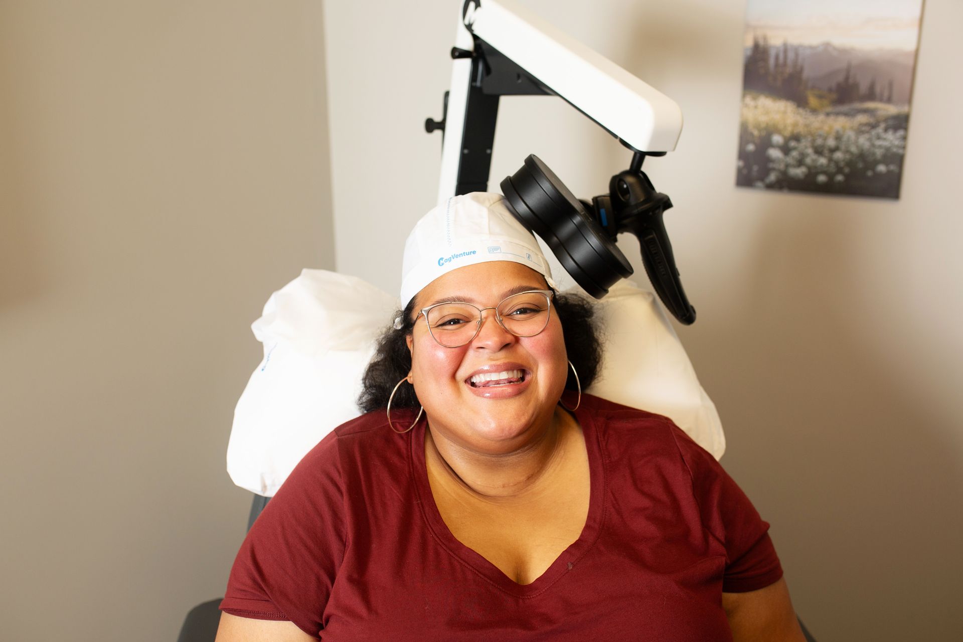 Woman in a white cap smiles while seated in a medical chair. A machine is positioned over her head.