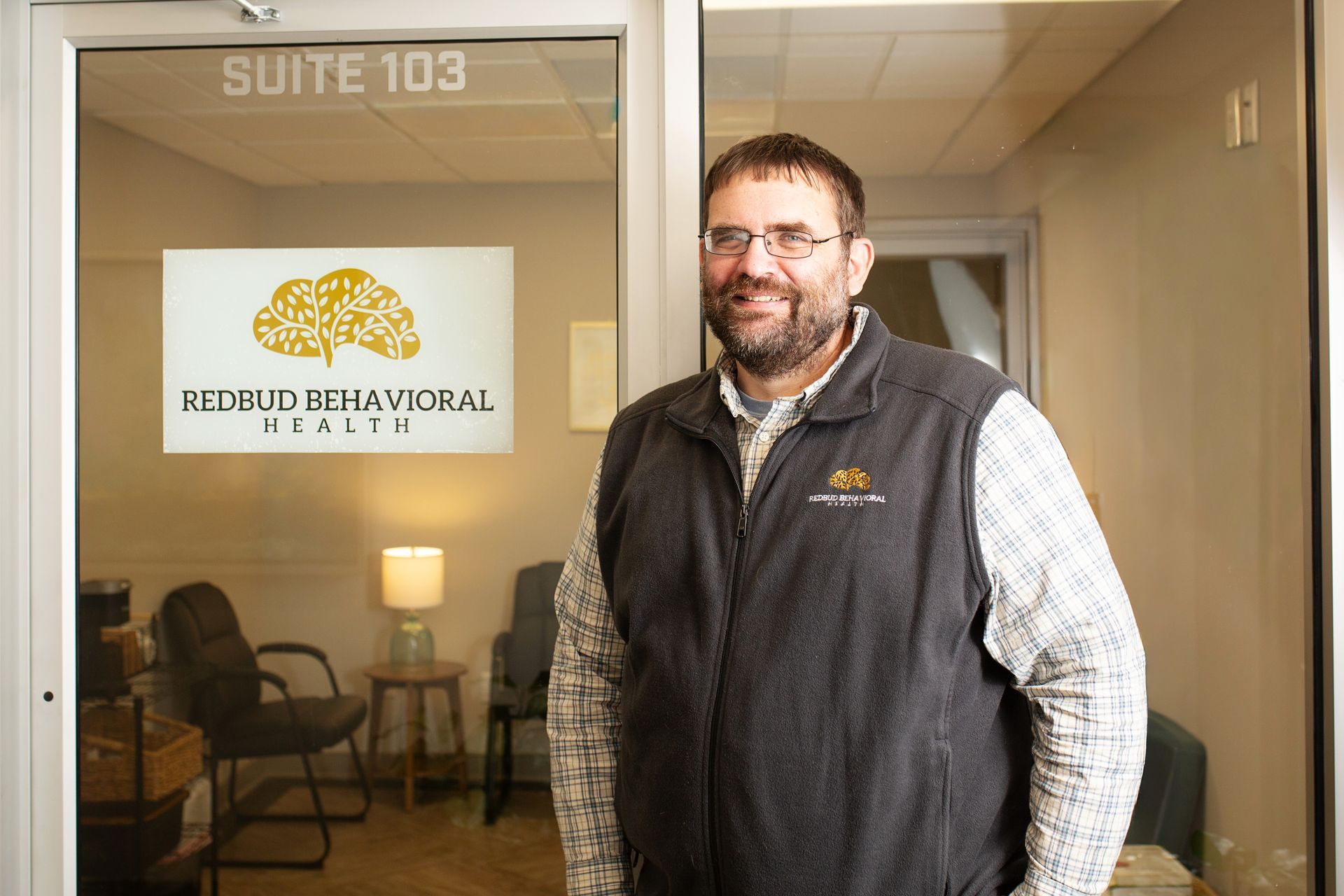 Man in vest stands outside 