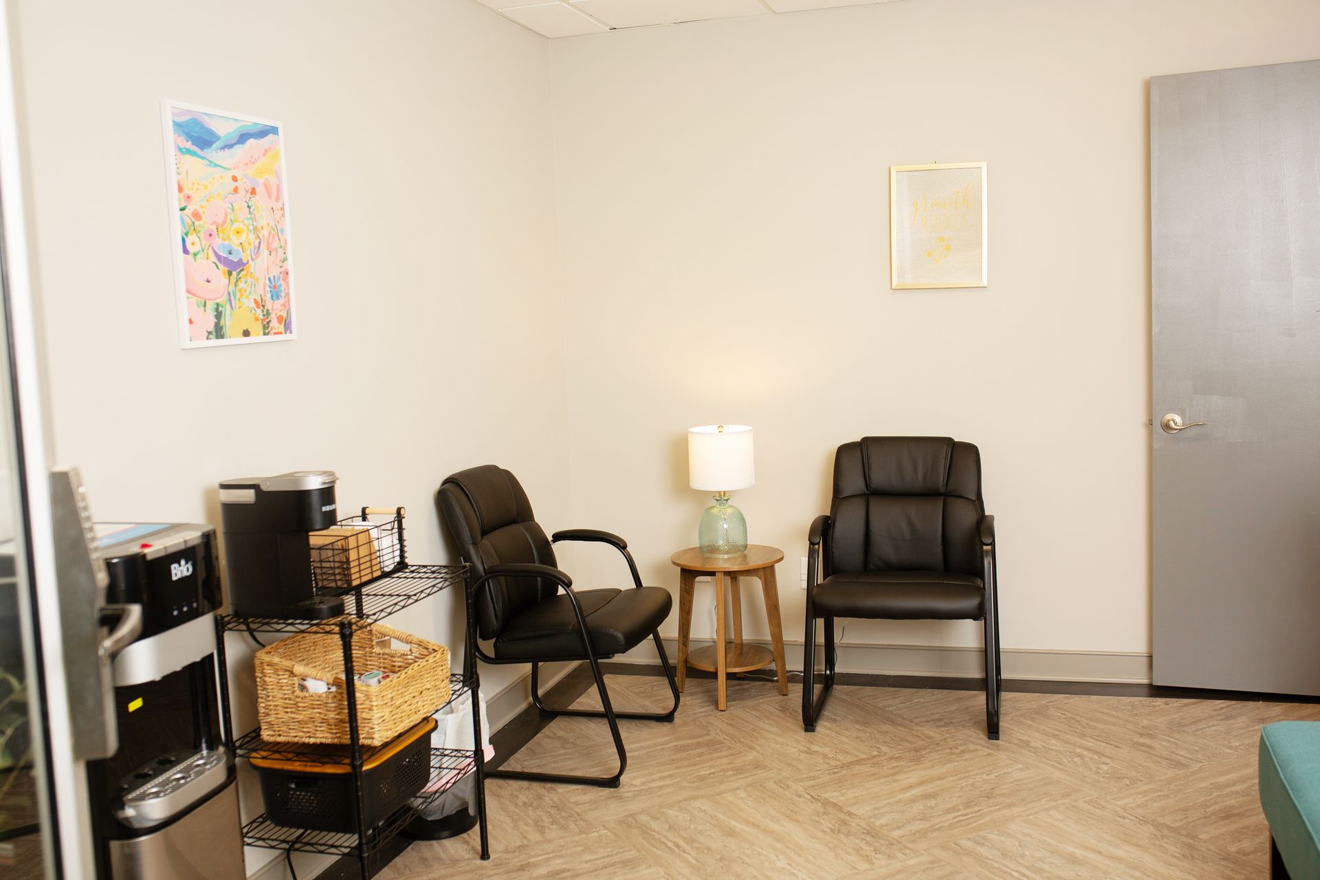 Waiting room with two chairs, a side table with a lamp, and a water cooler.