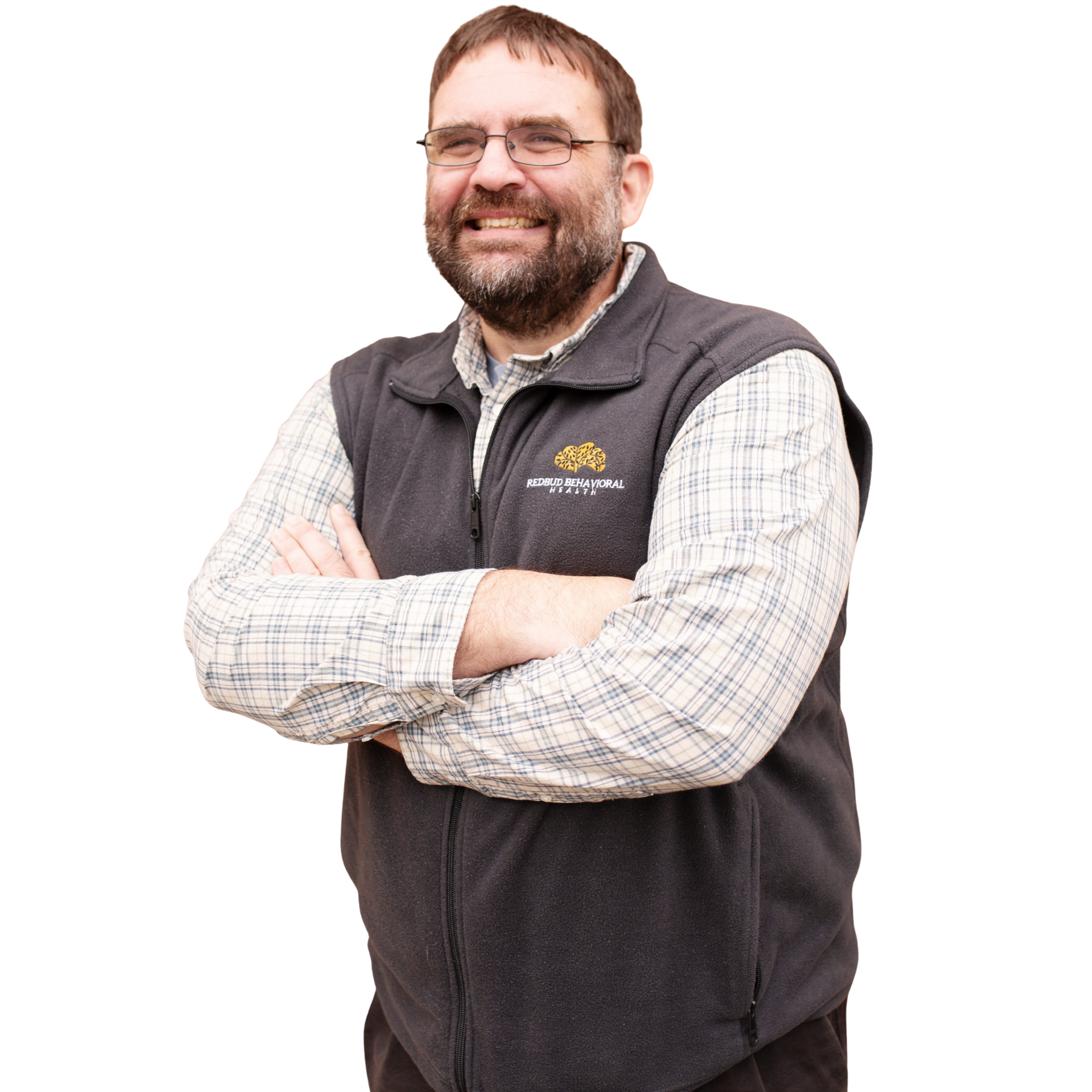 Man with beard and glasses smiles, arms crossed, wearing a fleece vest over a button-down shirt.