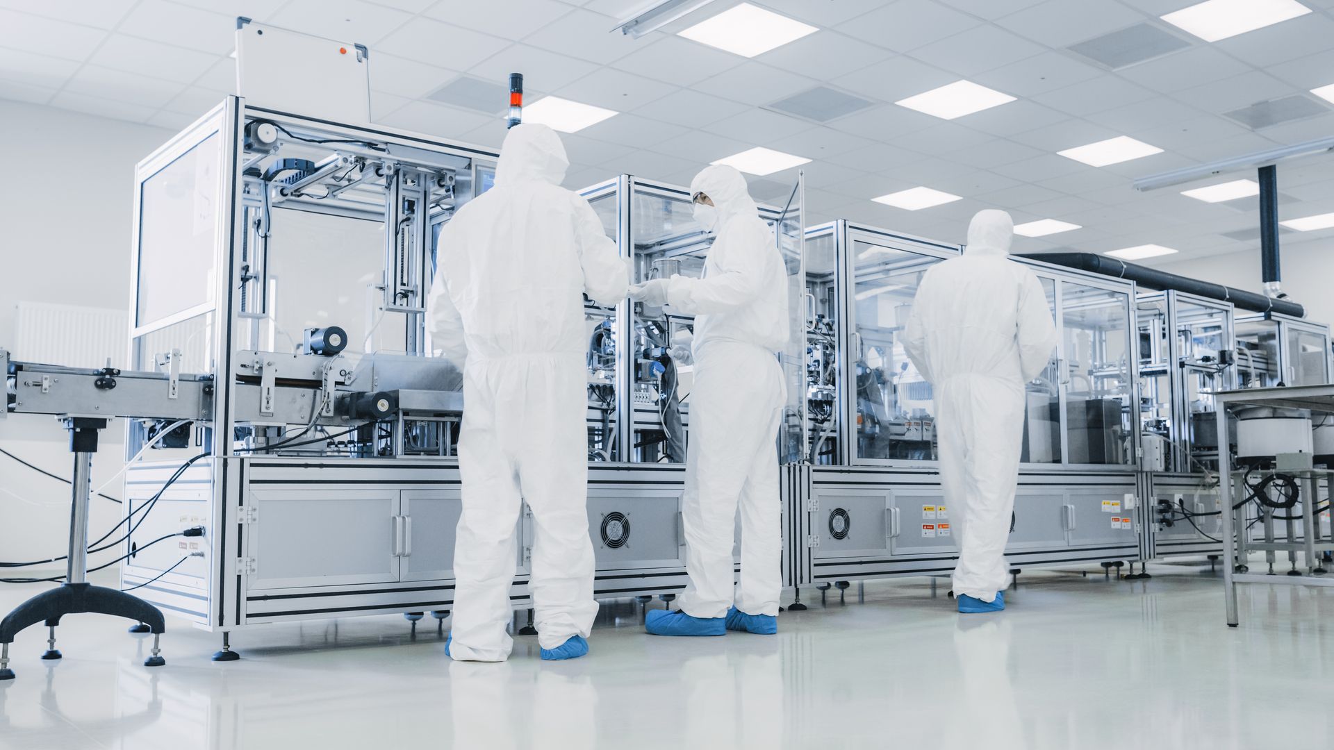 Lab technicians in cleanroom suits operating advanced laboratory equipment