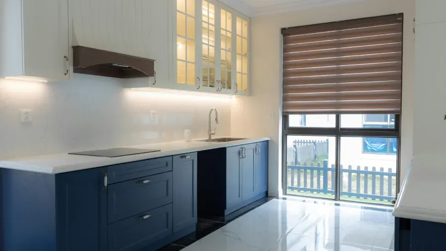 Blue and white kitchen with window, cabinet, and blinds.
