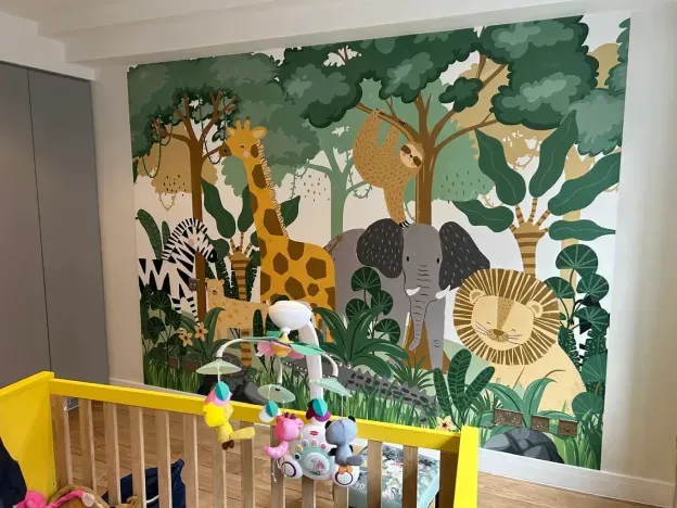 A jungle-themed mural with animals, next to a yellow crib.