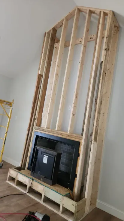 Wooden frame for a fireplace and TV installation against a white wall. The TV is installed in the center.