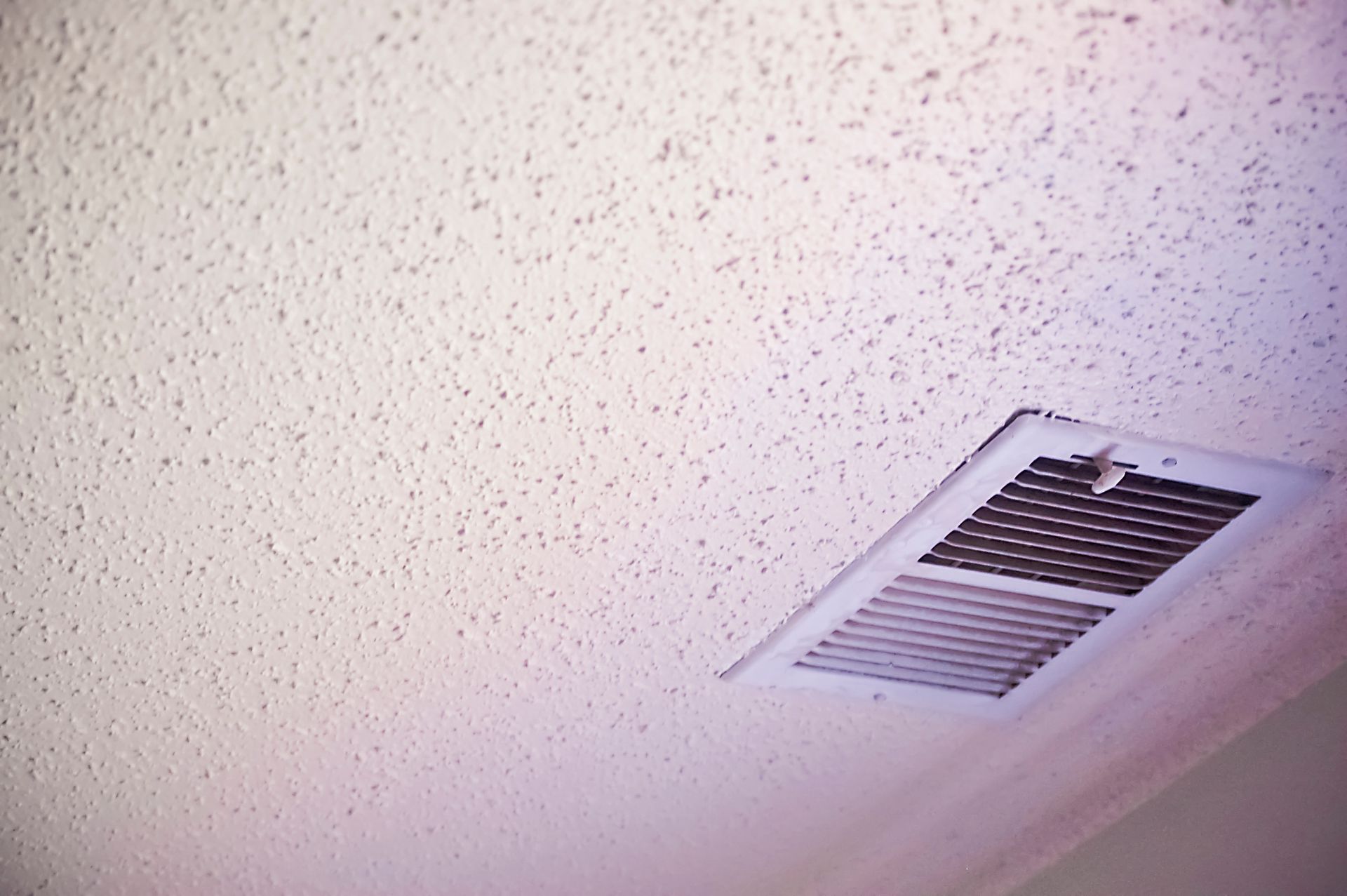 Textured white ceiling with a rectangular air vent.