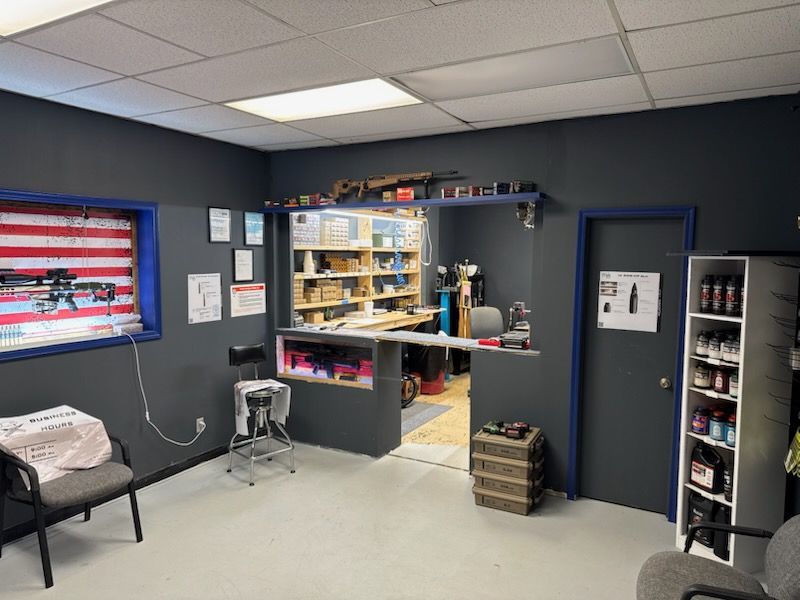 A room with a desk , chairs , shelves and an american flag on the wall.
