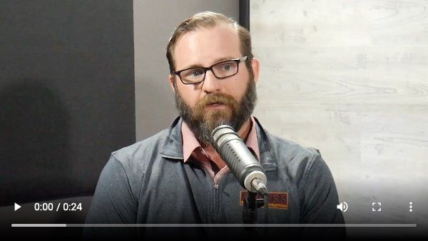 A man with a beard and glasses is talking into a microphone.
