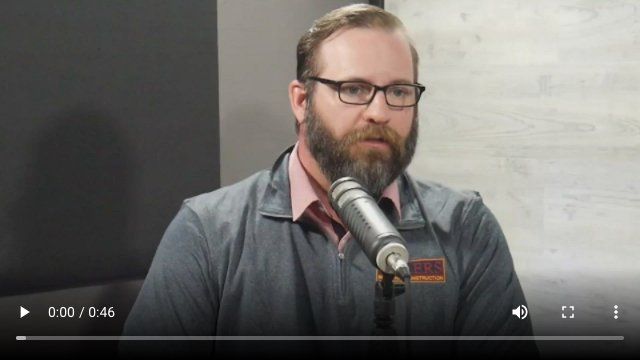 A man with a beard and glasses is talking into a microphone