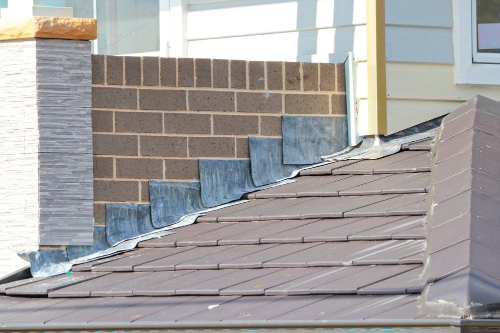 A roof with a chimney and a brick wall in the background