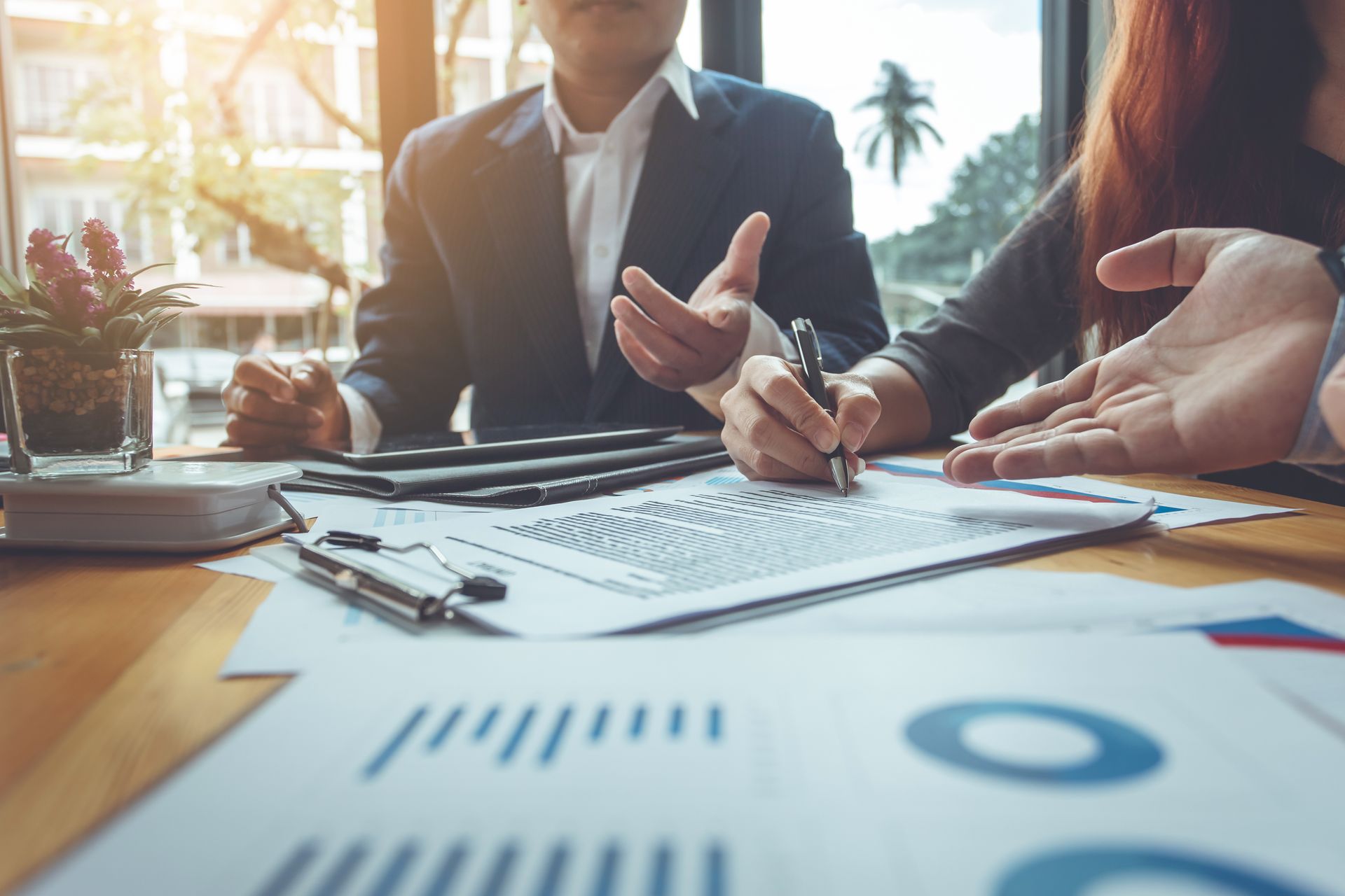 People in a meeting reviewing charts and notes on a conference table People in a meeting reviewing charts and notes on a conference table