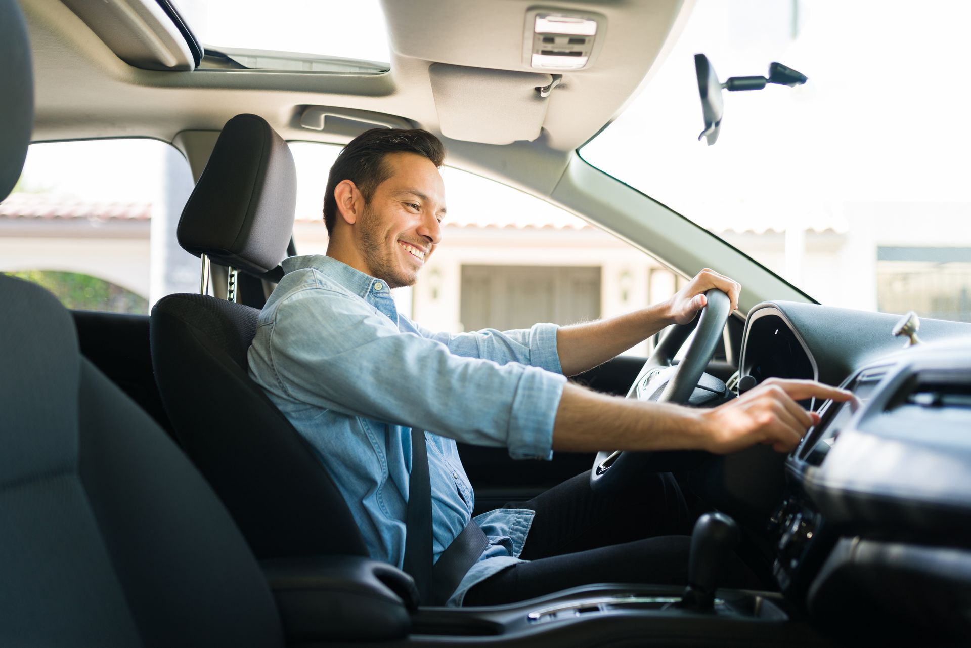 Man smiling while driving a car, hands on the wheel in a bright interior Man smiling while driving a car, hands on the wheel in a bright interior