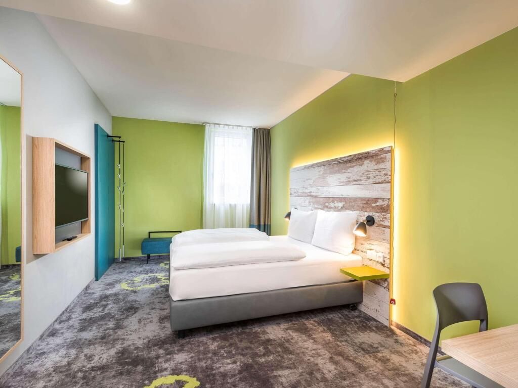 A hotel room with two beds , a desk and a television.