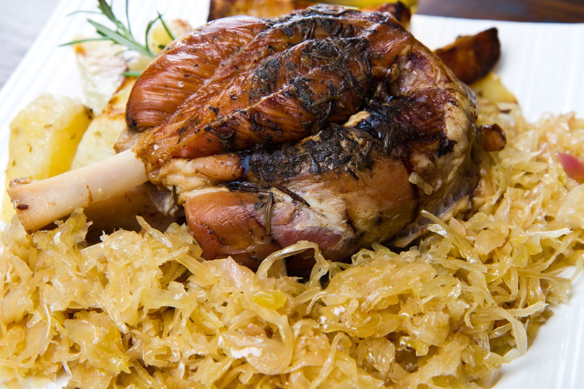 A plate of food with meat and sauerkraut on a table.