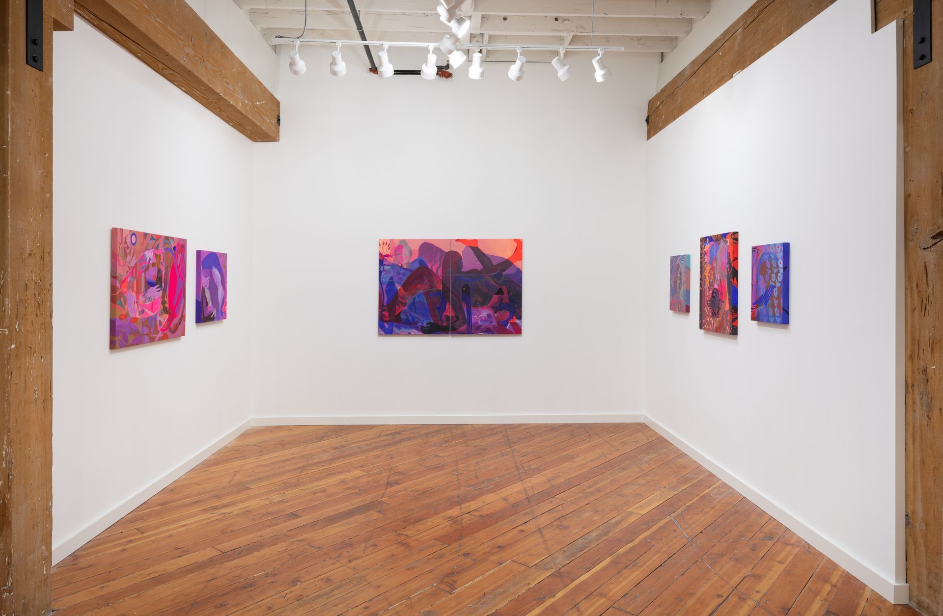 An art gallery with colorful abstract paintings by Emily Wise on white walls. Wooden beams and floors.