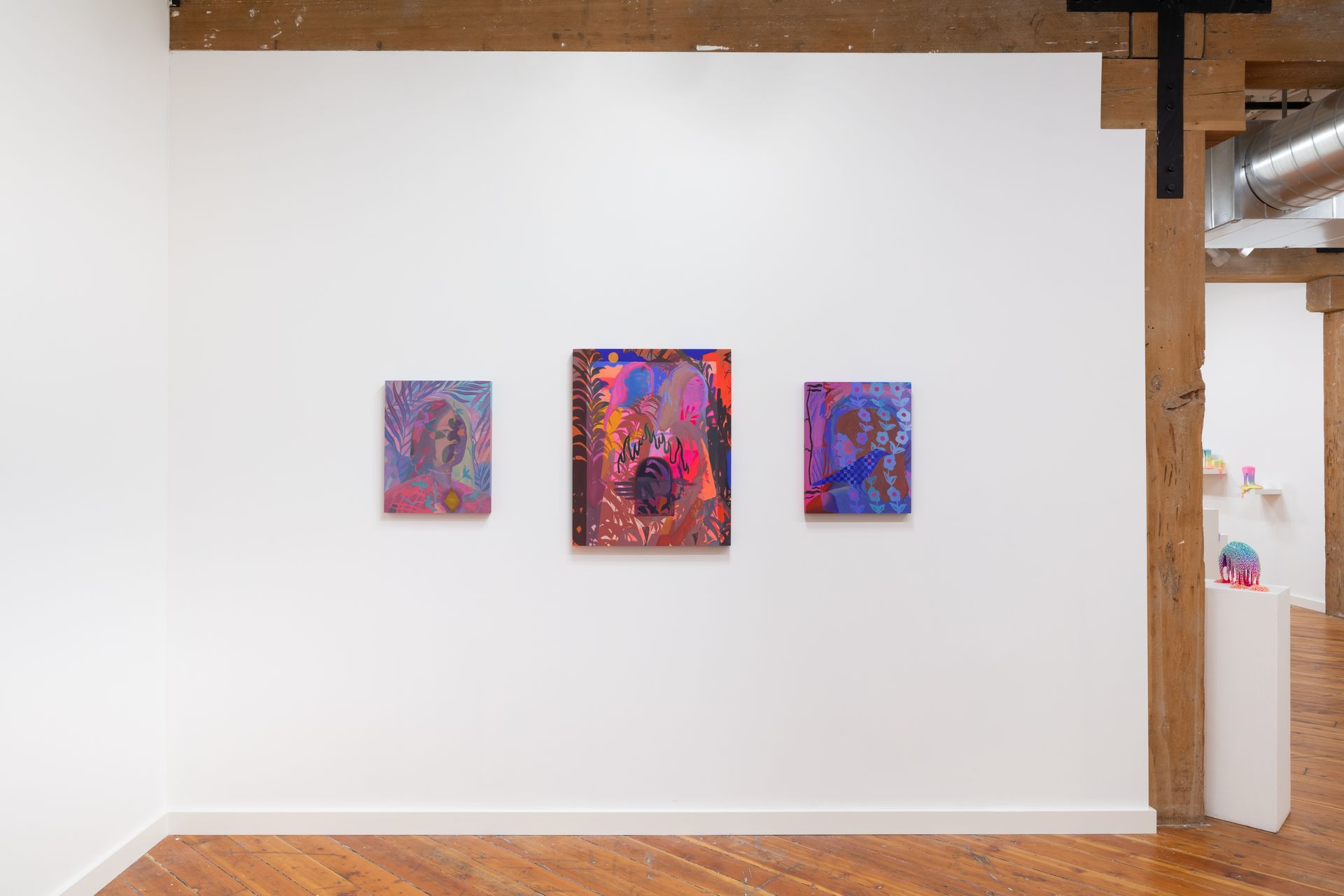 Three colorful abstract paintings by Emily Wise hang on a white gallery wall. Wooden beams and a doorway are visible.