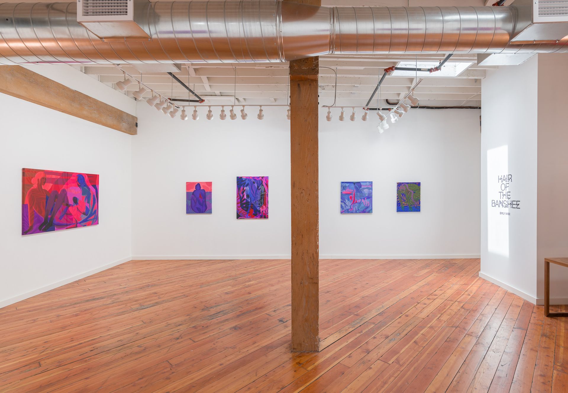 Art gallery interior with abstract paintings by Emily Wise on white walls and wooden floors.