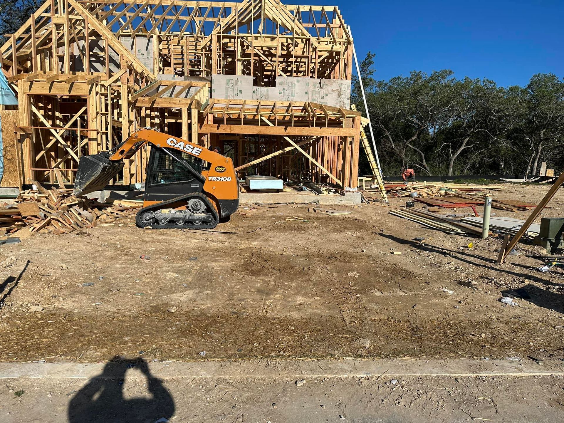 A Case skid steer loader on a construction site in front of a partially built house.