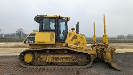 Yellow bulldozer on a construction site; it has tracks, a cab, and rippers.