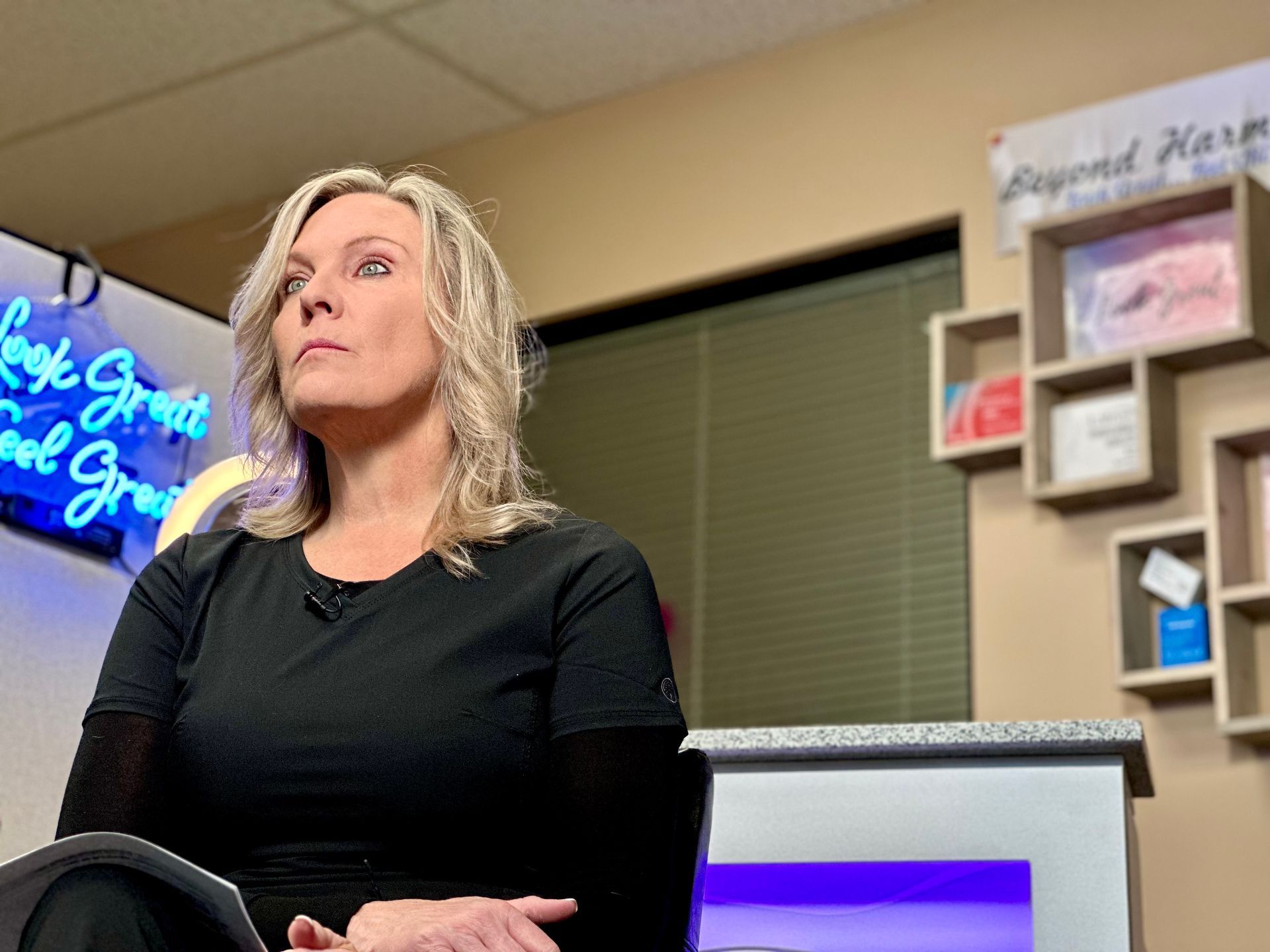 a woman sits in front of a sign for beyond harmony | Valencia, CA | Beyond Harmony Medical Spa
