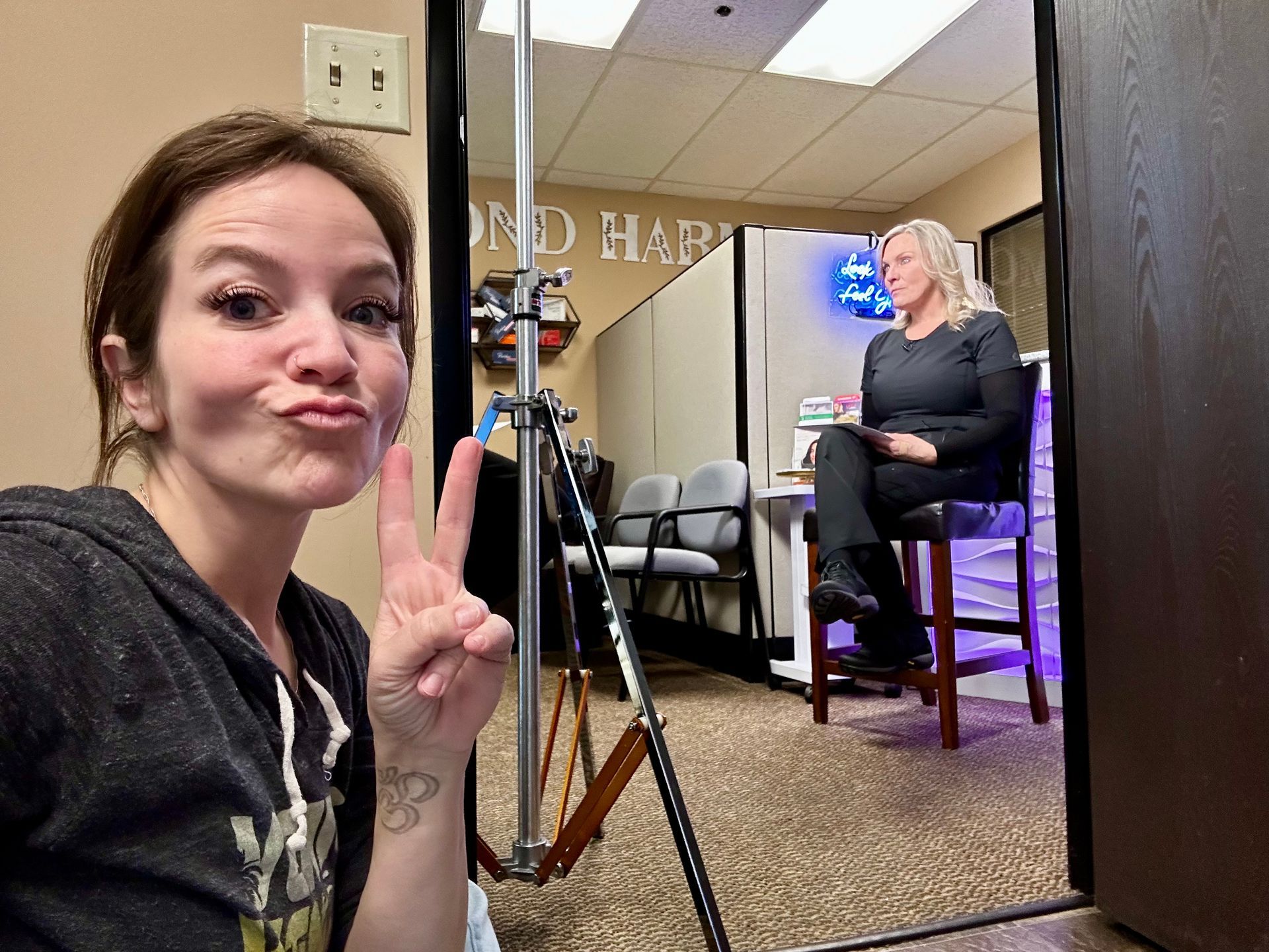 a woman sits in front of a sign for beyond harmony | Valencia, CA | Beyond Harmony Medical Spa