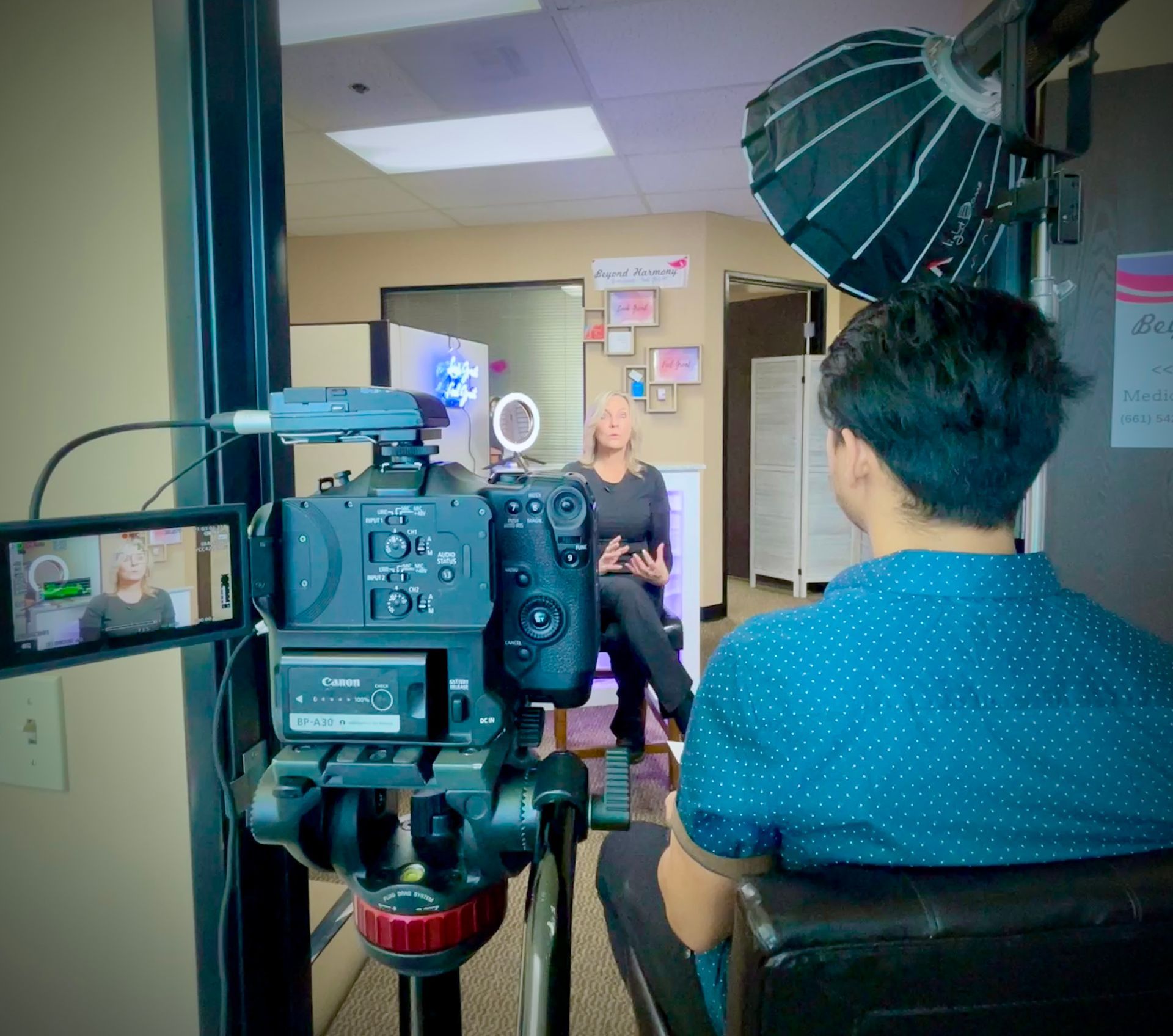 a woman sits in front of a sign for beyond harmony | Valencia, CA | Beyond Harmony Medical Spa