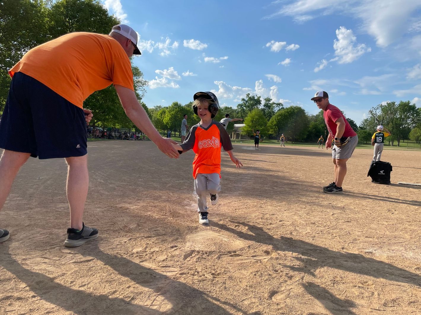 A 6u ball player getting a high five after scoring a run.