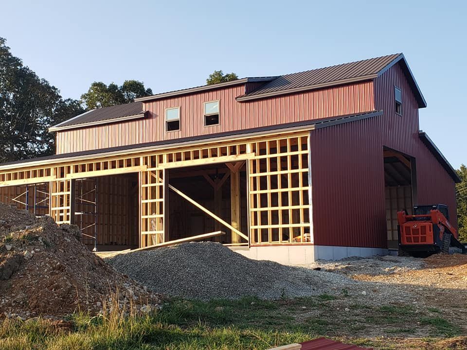 Red barn with white trim, brown roof, and small opening.