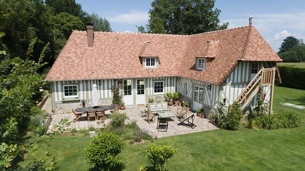 Une grande maison avec un toit de tuiles rouges et un patio devant à Deauville