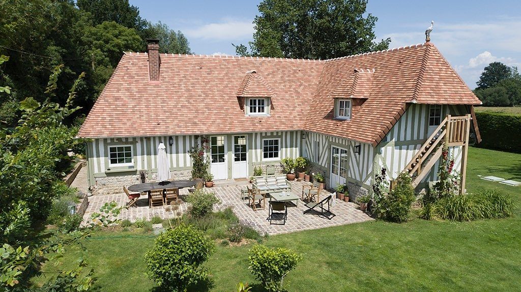 Une grande maison avec un toit de tuiles rouges et un patio devant.