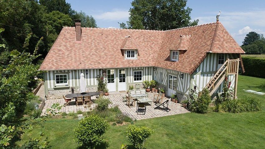 Une grande maison avec un toit de tuiles rouges et un patio devant  réalisé par mes services d'architecte d'intérieur