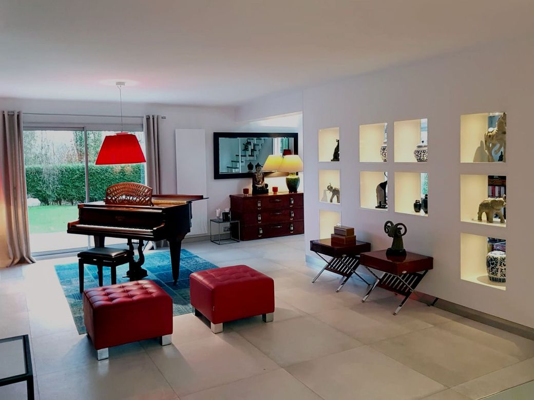 Un salon avec un piano et des poufs rouges  réalisé par mes services d'architecte d'intérieur à Deauville