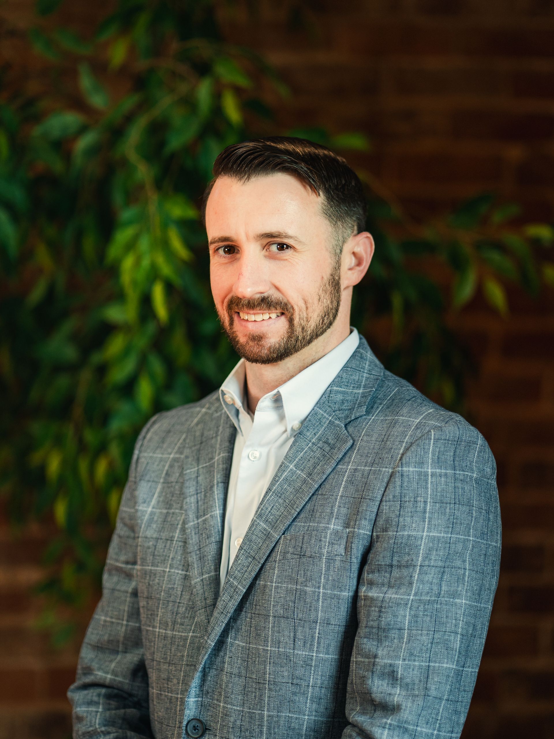 Woman with brown hair, smiling, wearing an orange top and necklace, set outdoors.