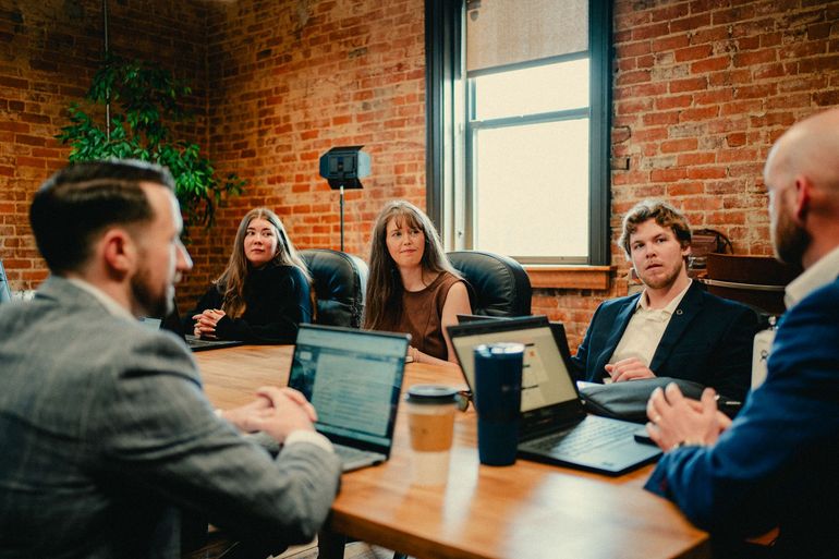 Father and son on sofa looking at tablet; mother and daughter in kitchen.