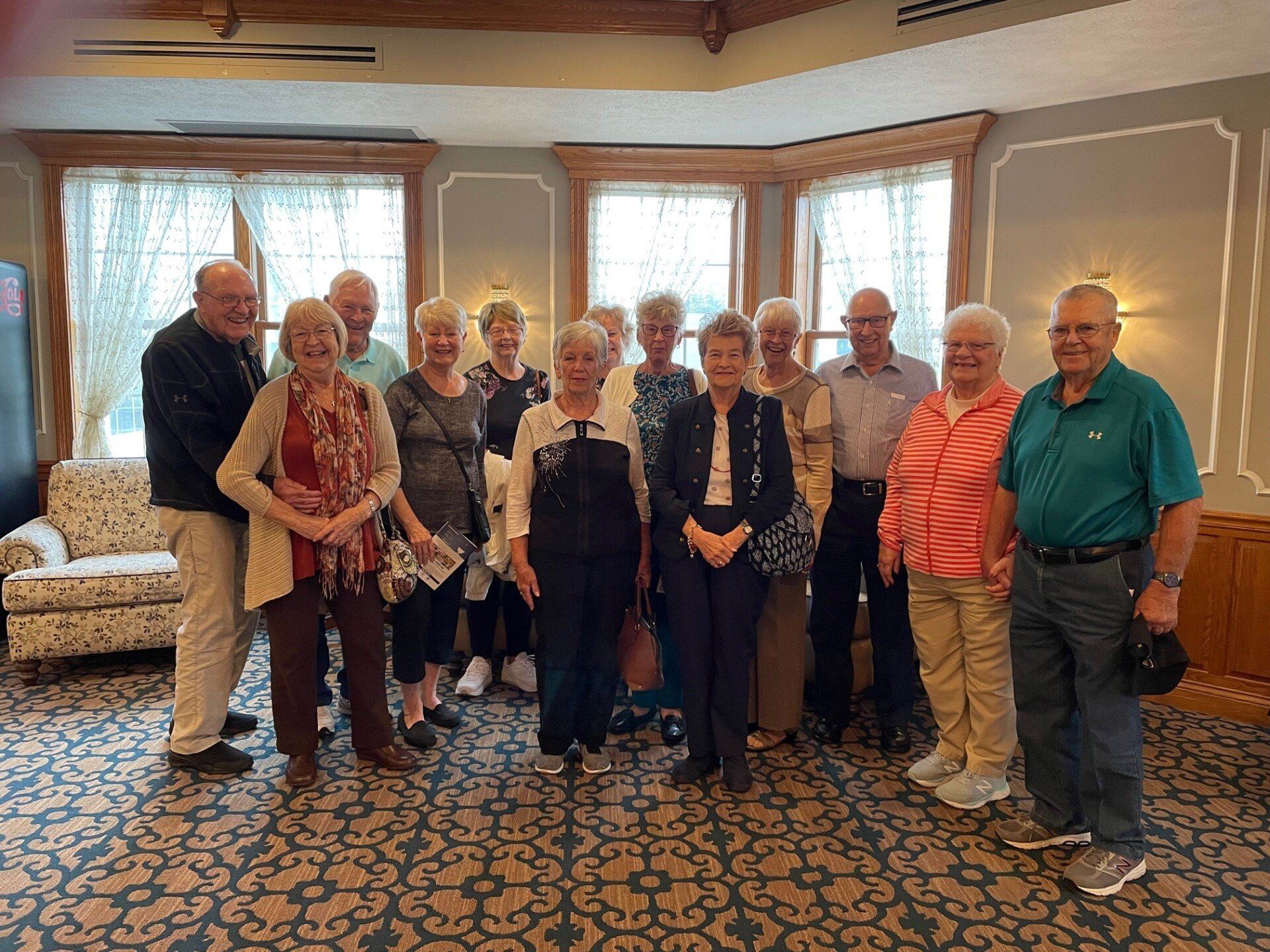 A person in religious garb shakes hands with a woman inside a church with a stained-glass window.